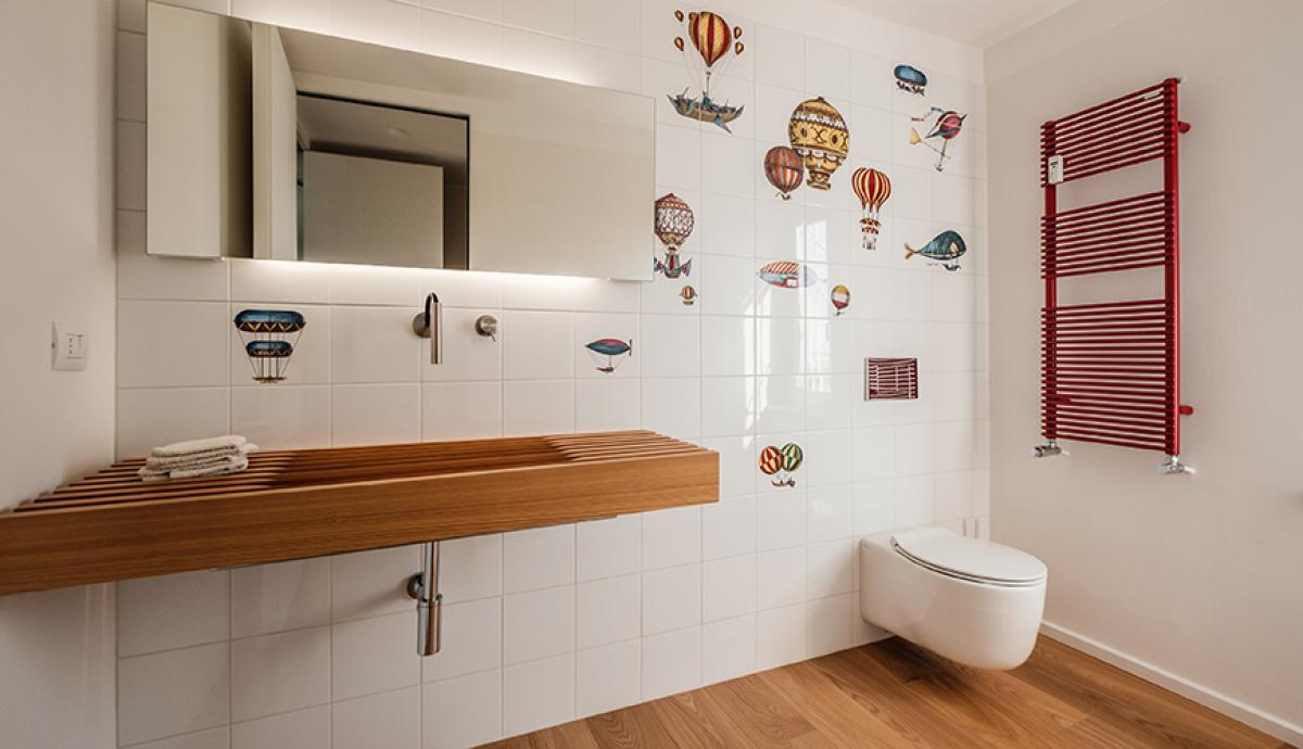 Bagno con piastrelle dal design giocoso e lavabo a doghe di legno