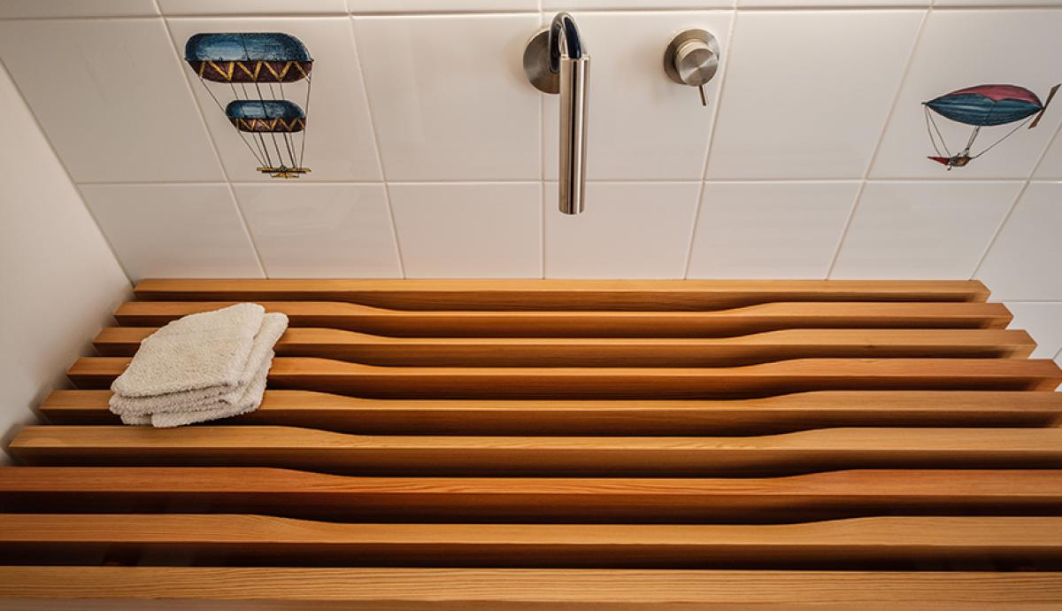 Bagno con piastrelle dal design giocoso e lavabo a doghe di legno