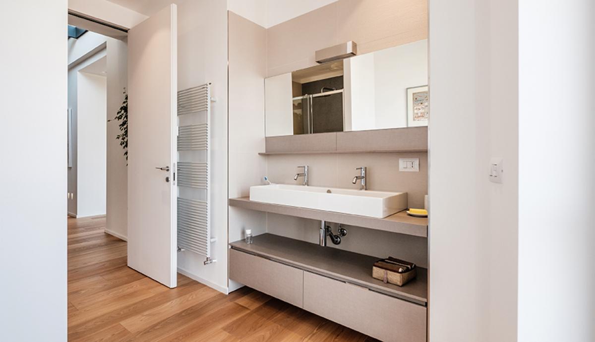 Appartamento dal design geometrico con pavimento unico in legno chiaro